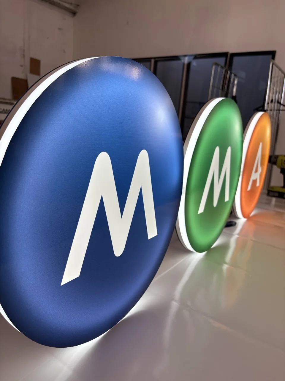 Trois enseignes lumineuses circulaires MMA bleue, verte et orange réellement fabriquées par SOLANDIS pour une agence de communication