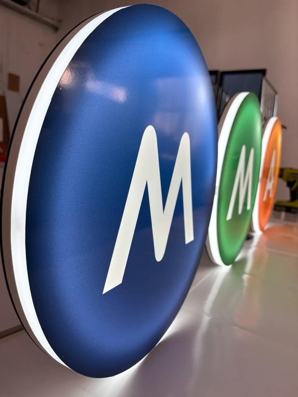 Trois enseignes lumineuses MMA réalisées par SOLANDIS, avec la face bleue au premier plan et les contours LED blancs visibles