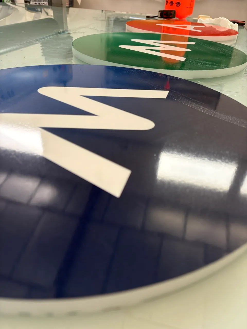 Vue rapprochée des trois faces d'enseignes MMA bleue, verte et orange disposées sur une table dans l'atelier SOLANDIS
